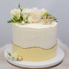 a white and gold wedding cake with flowers on top