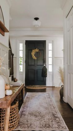 a hallway with a black door and rug on the floor next to an entryway