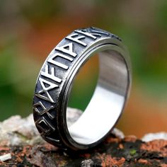 a wedding ring with the word alaska engraved on it sitting on top of a rock