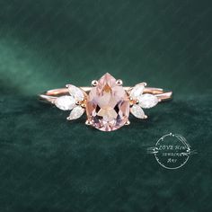 a pink diamond ring with three pear shaped diamonds on the side and two pear shaped white stones