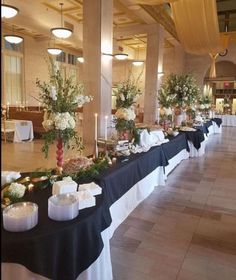 a banquet hall with tables covered in black tablecloths and white flowers on them