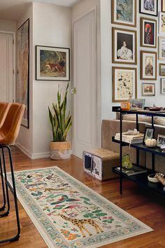 a living room with pictures on the wall and a rug in front of a chair