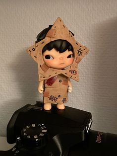 a small doll sitting on top of a camera