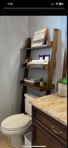 a bathroom with a toilet and wooden shelves