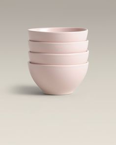 four pink bowls stacked on top of each other in front of a gray background,