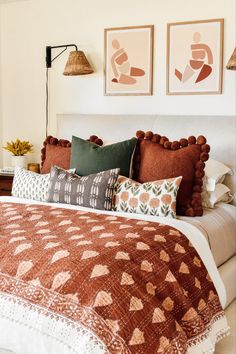 a bed with many pillows on it and pictures above the headboard in a bedroom