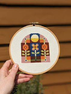 a hand is holding up a cross - stitch embroidery hoop with an image of a bus on it