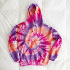 a purple and red tie - dyed hoodie on a white sheet