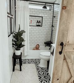 a bathroom with a black and white tile floor, shower curtain, toilet and bathtub