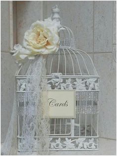 a white birdcage with a flower on it and a card in the cage