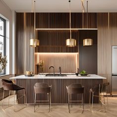 a modern kitchen with an island and bar stools next to the countertop, along with gold pendant lights