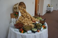 an arrangement of food on a table in a banquet hall or conference room with white linens