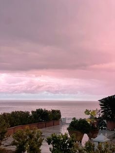 the sky is pink and cloudy over the ocean