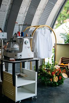 a sewing machine sitting on top of a white table next to a green plant and potted plants