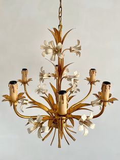 a gold chandelier with white flowers hanging from it