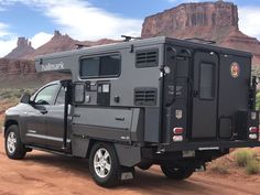 a truck with a camper attached to it parked in the desert