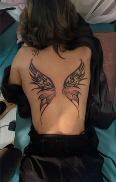 a woman laying on top of a bed with a tattoo on her back and shoulder