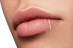 a woman's lips with a gold ring on top of her lip and the tip of her nose