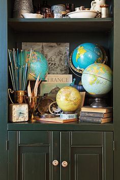 an open bookcase with books, globes and other items on top of it