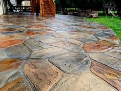 a stone patio with steps leading up to the back door and stairs in the background