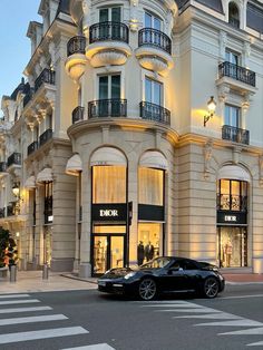 a black sports car parked in front of a building with windows and balconies