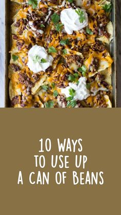 nachos with meat, cheese and sour cream on a baking sheet covered in tortilla chips