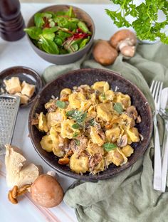 a bowl filled with pasta and mushrooms next to other food on a tablecloths