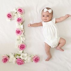 a baby is laying next to a flower letter