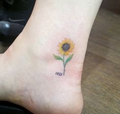 a small sunflower with the word leo tattooed on it's foot, sitting on a wooden floor