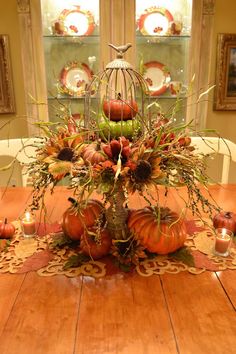 a table topped with lots of pumpkins and other fall decorations on top of a wooden table