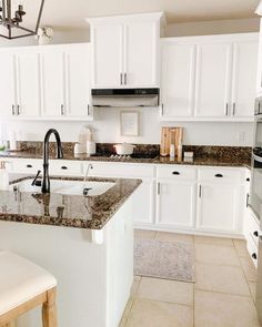 a kitchen with white cabinets and granite counter tops, along with an island in the middle