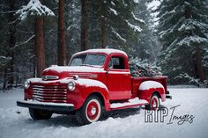 an old red truck is parked in the snow near some trees and evergreens with christmas decorations on it