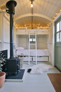 a room with bunk beds and a wood stove in it, next to a potted plant