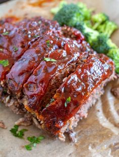 meatloaf with sauce and broccoli on a piece of parchmented paper