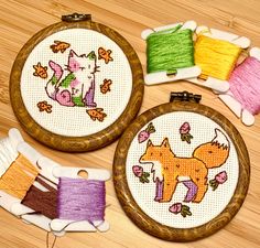 three cross stitch hoops with different designs on them, one has a cat and the other has a dog