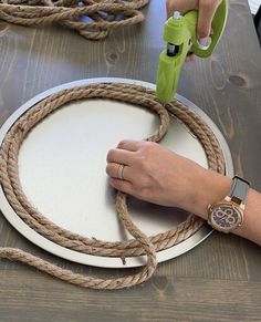 a person is using a green sprayer on a white plate that has rope around it