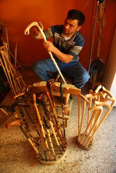 a man is working on some kind of chair made out of wooden sticks and branches