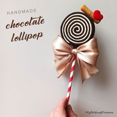 a hand holding a lollipop on top of a piece of paper with a candy stick sticking out of it