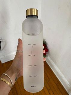 a person holding up a water bottle with the names of different types of water in it