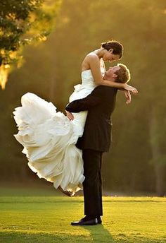 a bride and groom are dancing on the golf course in their wedding attire with trees in the background