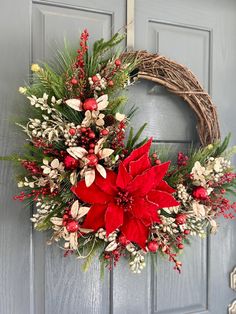 a wreath with poinsettis and greenery hangs on a door