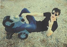 a man laying on the ground next to a toy motorcycle with wheels and arms outstretched