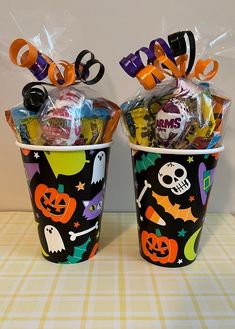 two halloween buckets with candy and candies in them sitting on top of a table