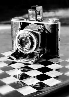 an old camera sitting on top of a checkered table