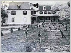 an old black and white photo of people playing in front of a house with trees