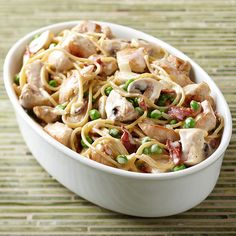 a white bowl filled with pasta and vegetables on top of a table next to a fork