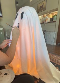 a woman is painting a ghost with paintbrushes