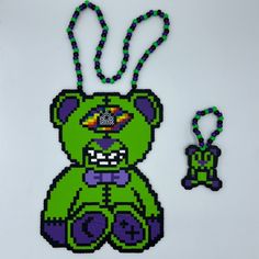 a green teddy bear with a purple bead necklace