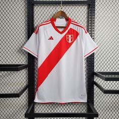 a white and red soccer jersey hanging on a rack