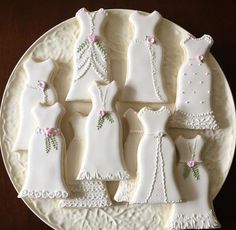 decorated cookies in the shape of brides dresses on a white plate with pink flowers